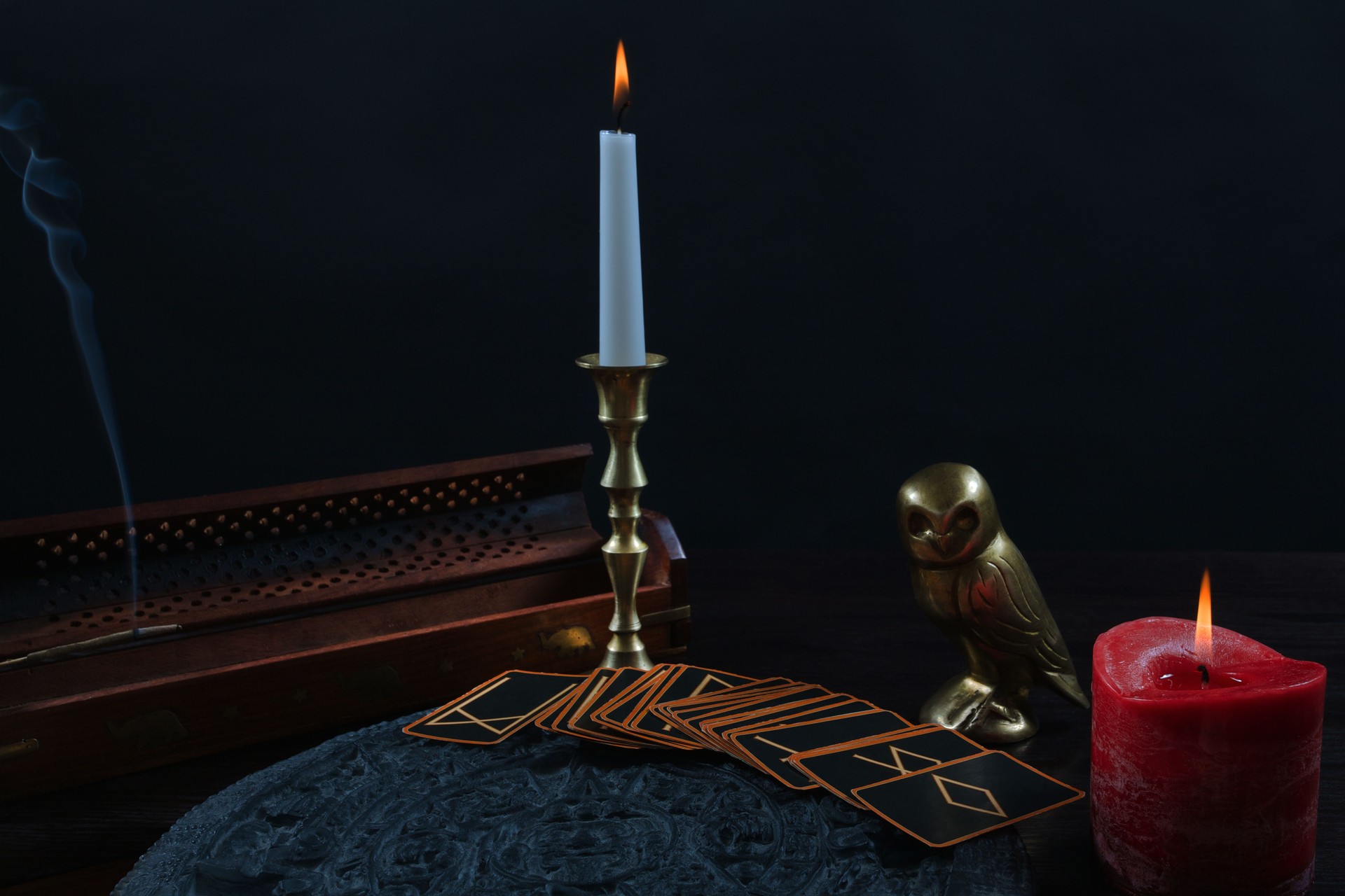 Magic ritual with runes cards and candles on black