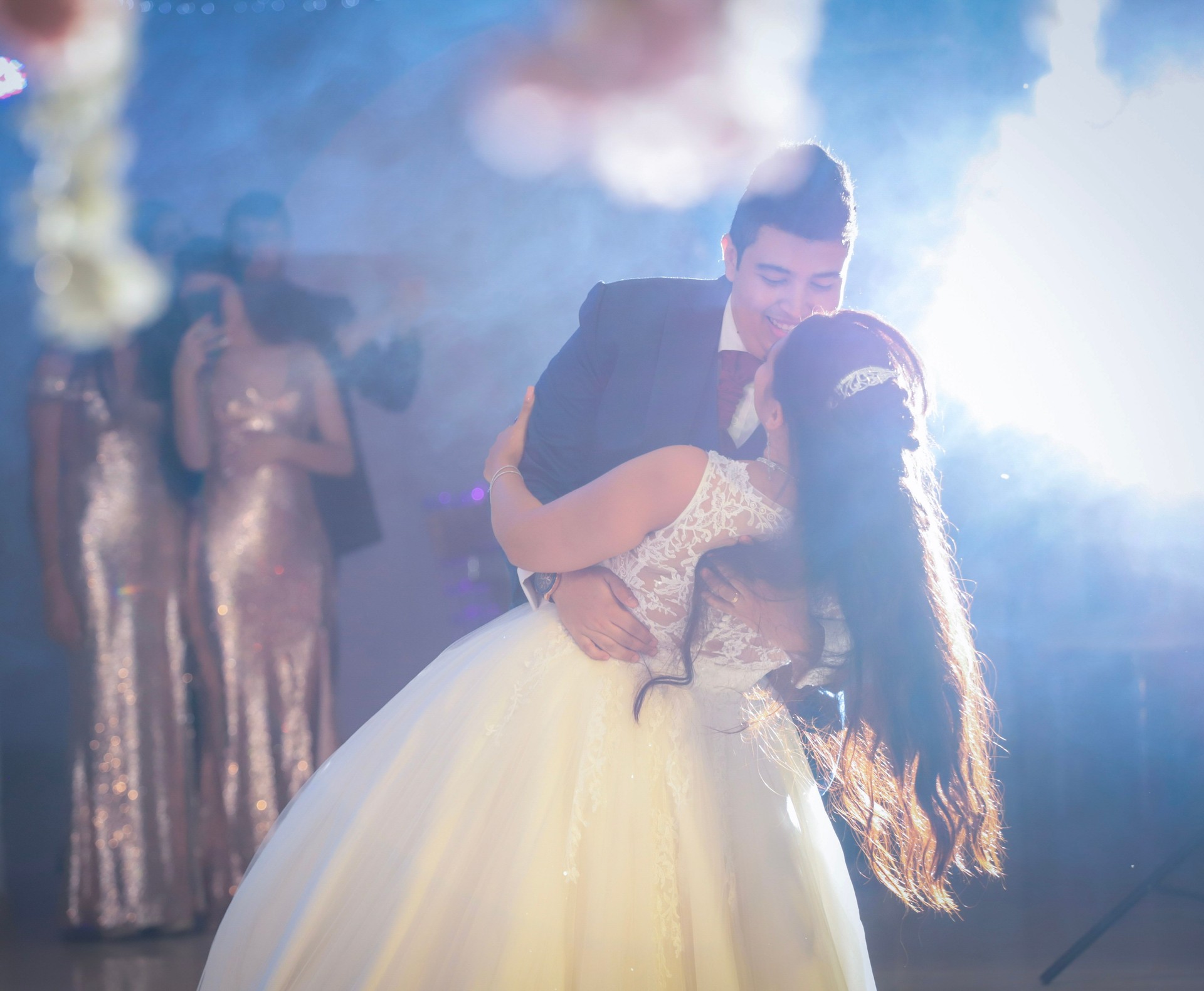 Joyful couple dances together, surrounded by friends, creating magical memories under vibrant lights at a wedding celebration